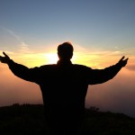 Man praying silhouetted on evening sky