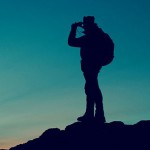 Hiker on mountain top looking at sunrise